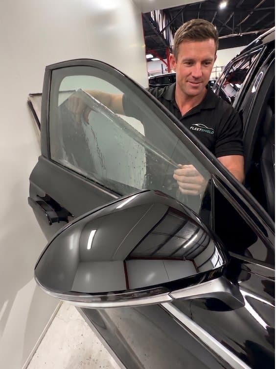 FleetShield installer working on a tinted side window