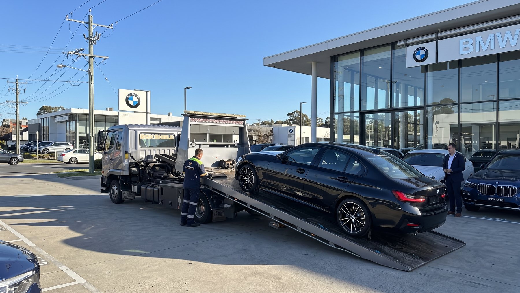 A vehicle being loaded onto FleetShield transport outside a dealership